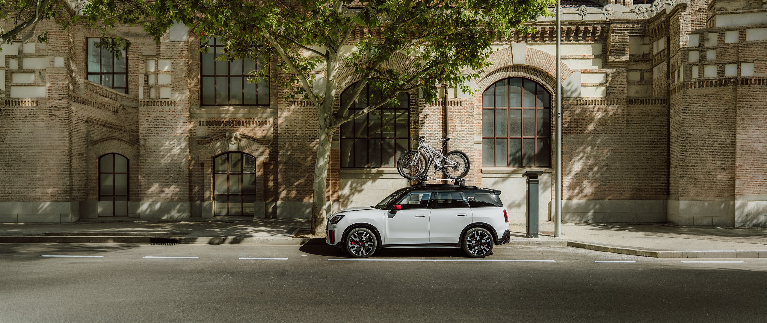 Vorderansicht des MINI Aceman in Indigo Sunset Blue mit MINI Fahrraddachträger mit Mountainbike und MINI Dachbox 320.